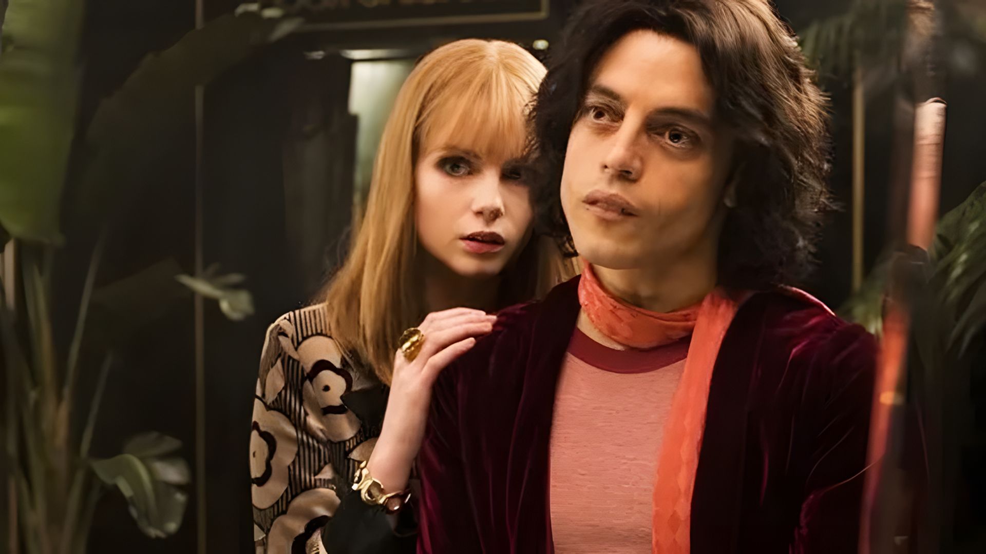 Um homem e uma mulher em fatos dos anos 70 estão junto ao espelho