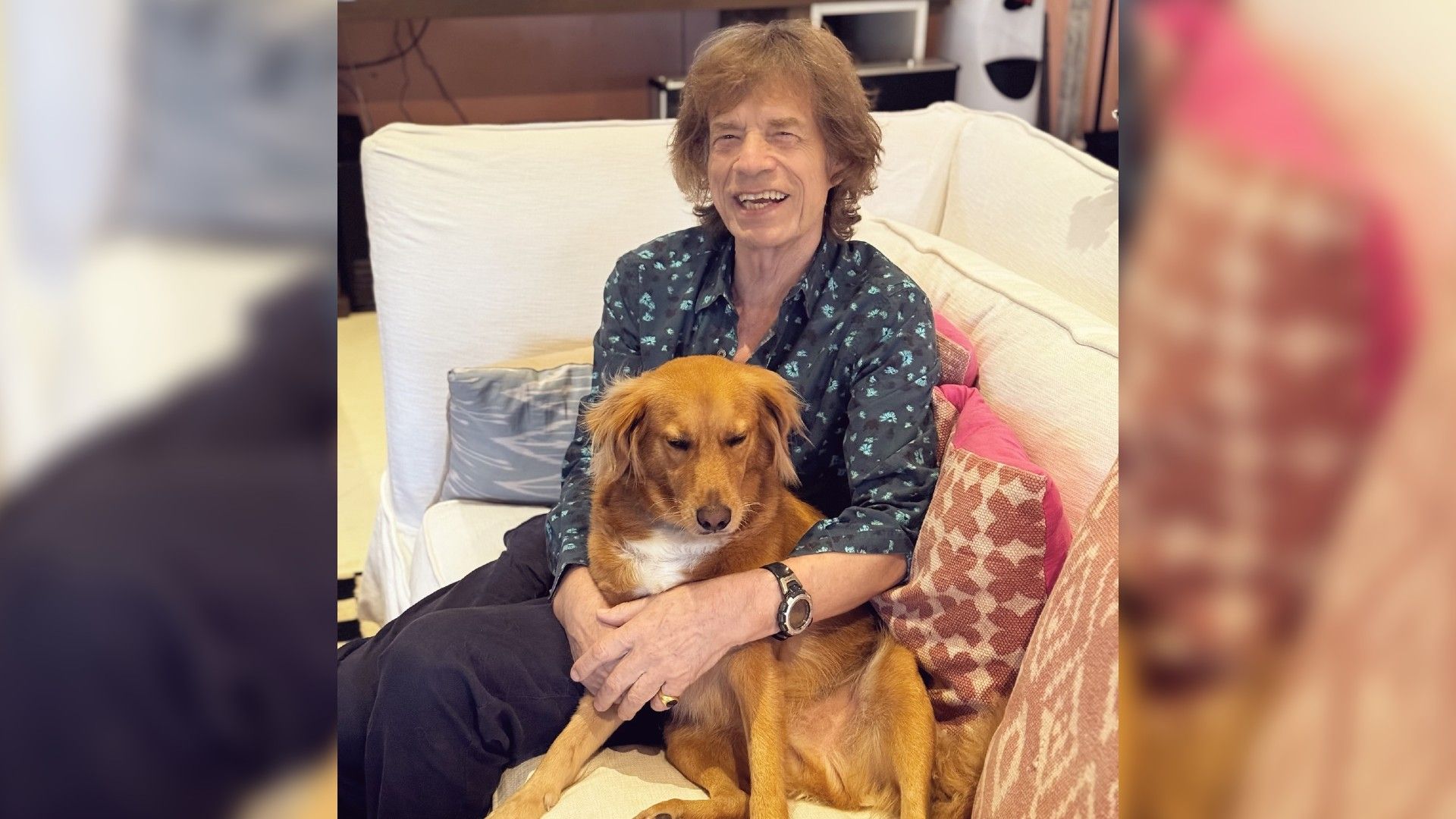 Um homem idoso com cabelo comprido está sentado no sofá abraçando um cão
