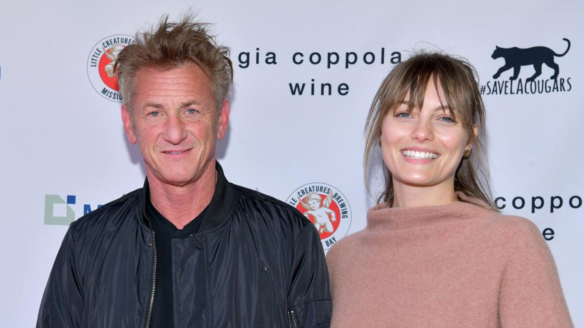 Sean Penn de casaco preto e Leila George de camisola bege