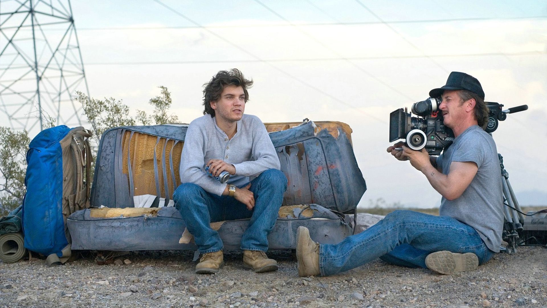 Sean Penn sentado no chão a filmar um jovem num sofá deteriorado com uma câmara de cinema