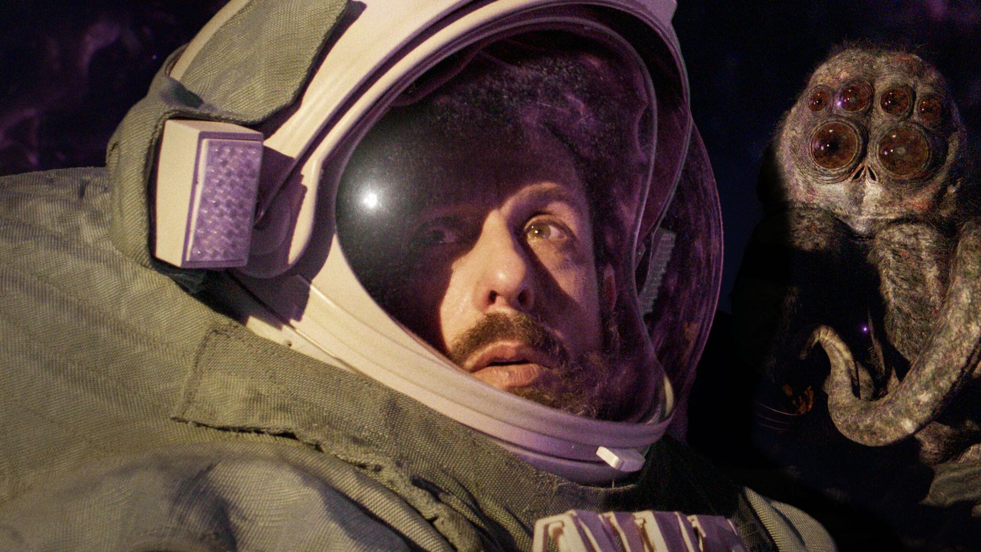 Adam Sandler num capacete de astronauta, com um inseto gigante à direita