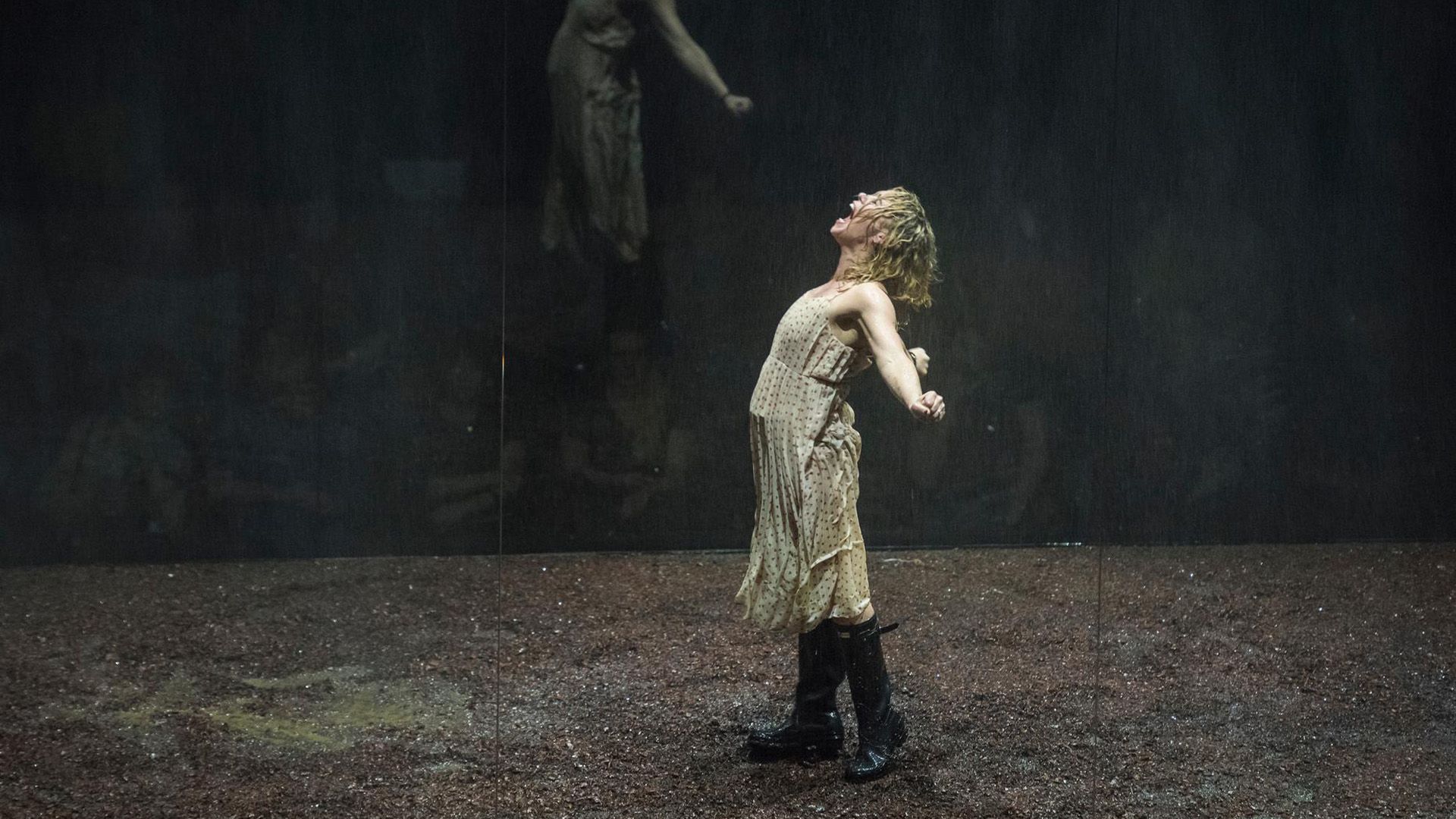 Billie Piper num vestido claro e botas altas, de pé no palco, de braços abertos, a gritar