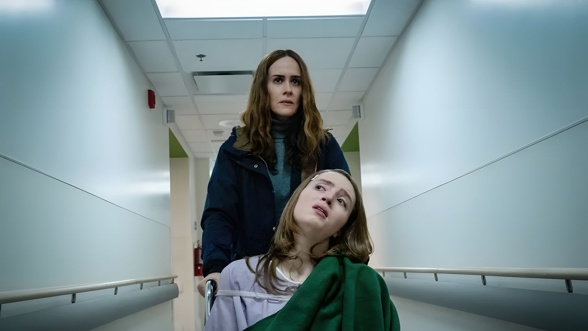 Jennifer Connelly empurra Alice Englert numa maca, uma cena do filme Bad Behaviour