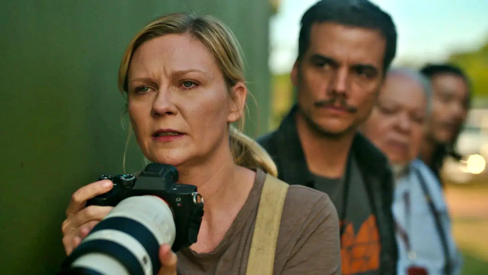 Kirsten Dunst segura uma câmara e olha em frente com tensão
