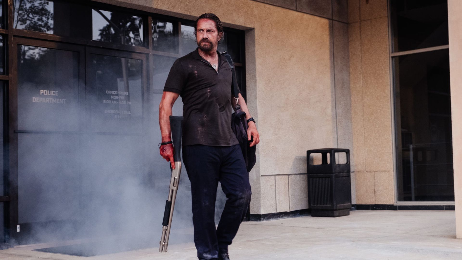 Gerard Butler de pé com uma arma, cena do filme