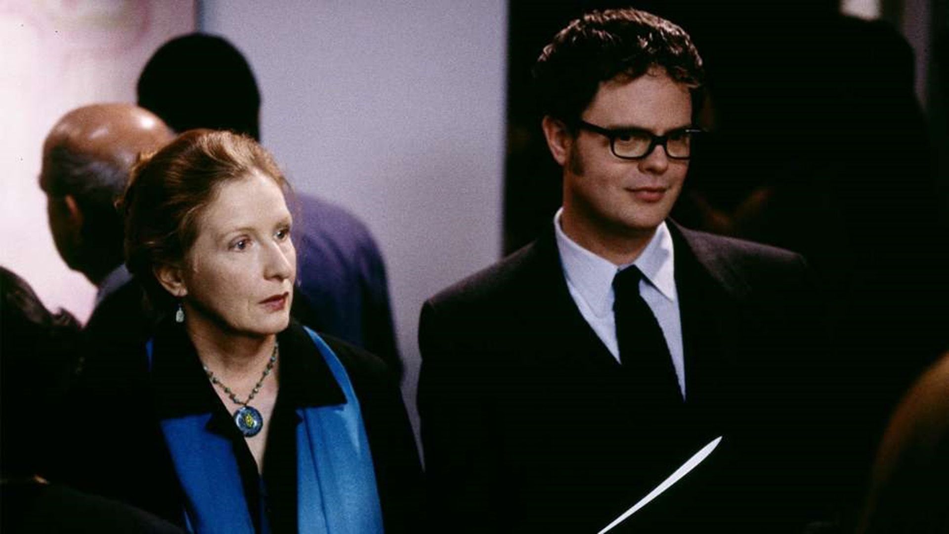 Rainn Wilson de óculos e blazer, ao lado de Frances Conroy com um lenço azul