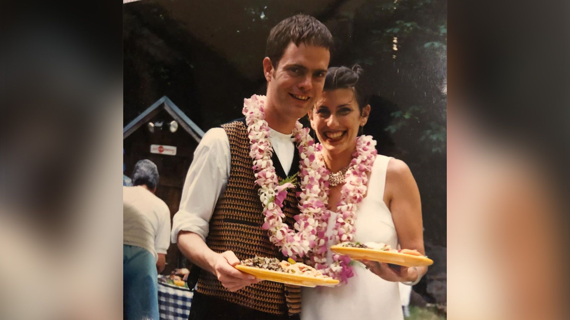 Rainn Wilson e Holiday Reinhorn jovens com colares de flores cor-de-rosa ao pescoço