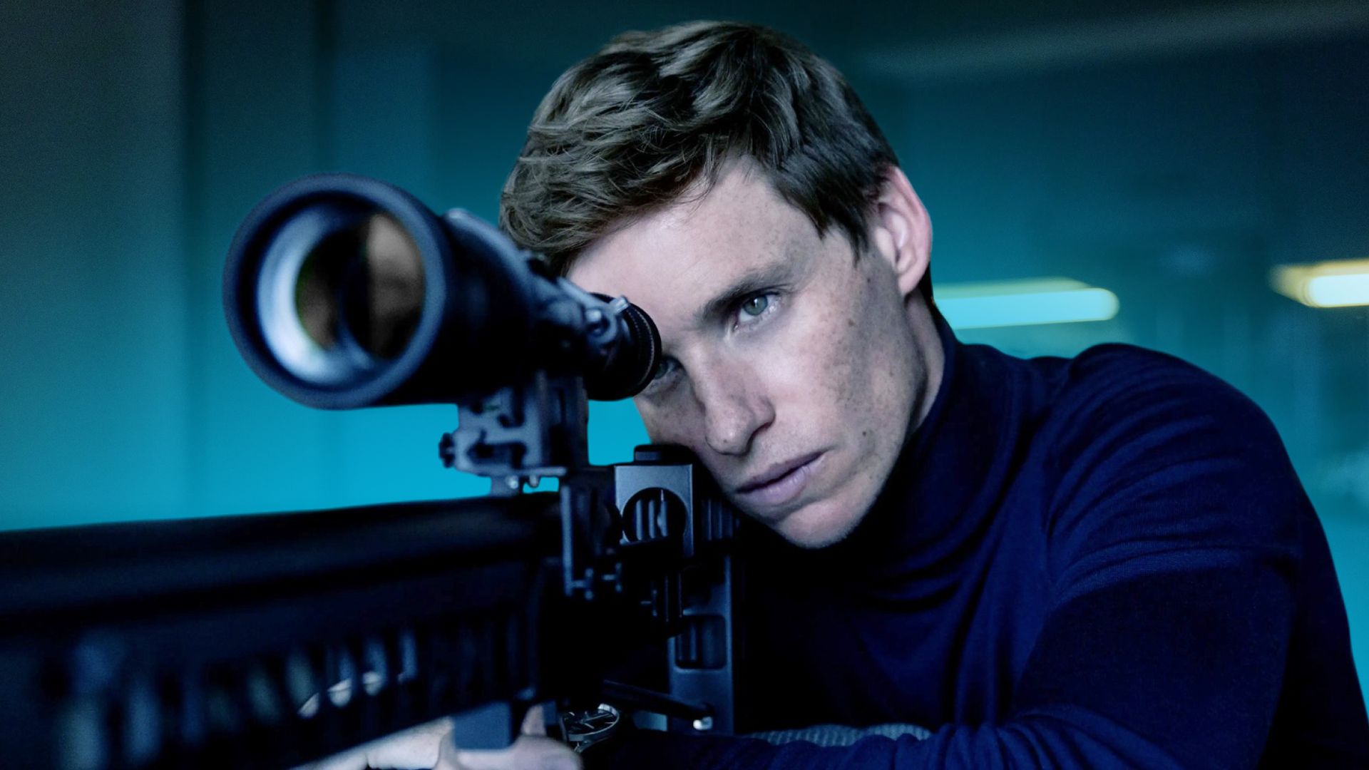 Eddie Redmayne a olhar através de uma mira de rifle de precisão