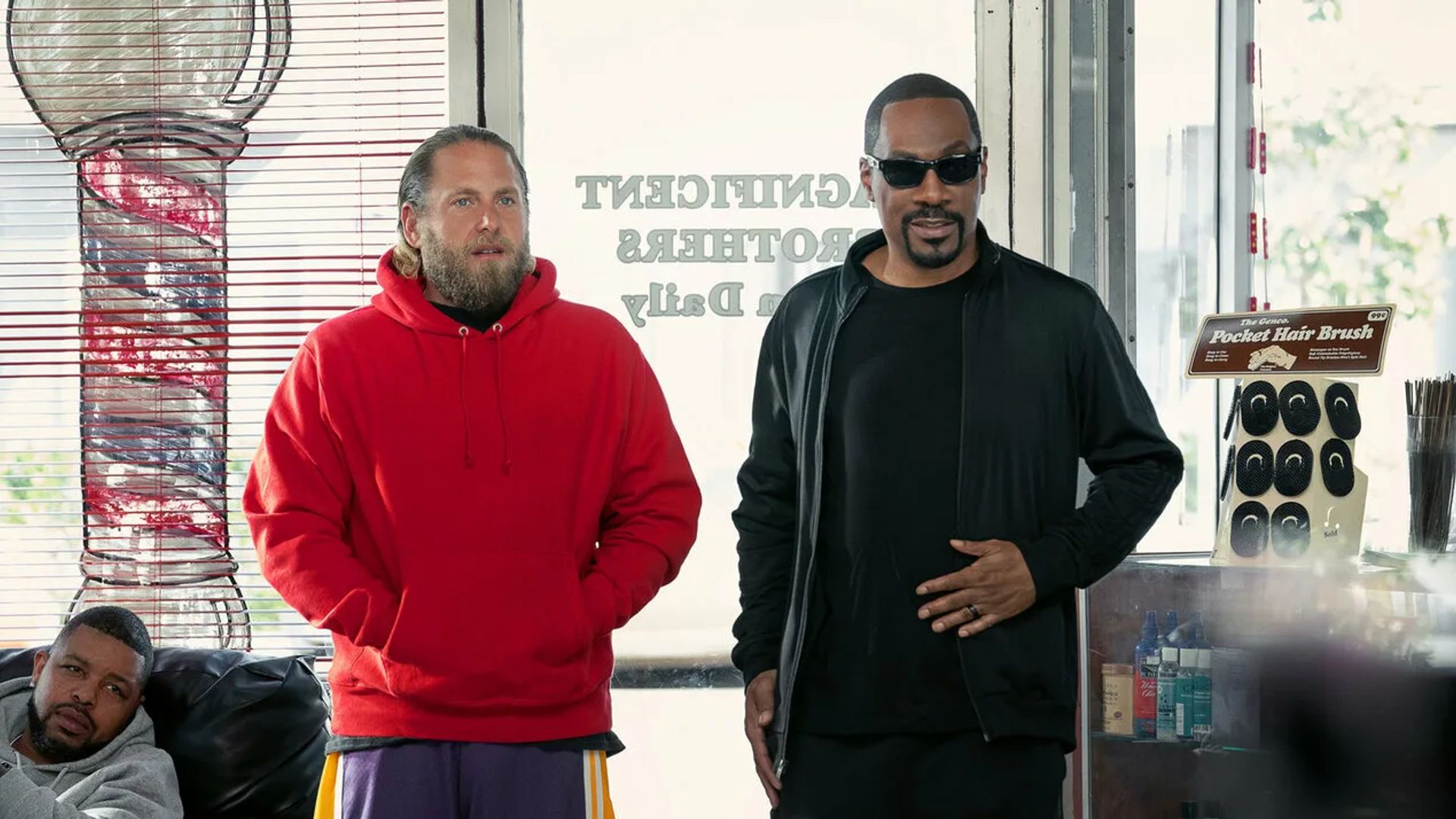 Jonah Hill num hoodie vermelho e Eddie Murphy todo de preto numa loja