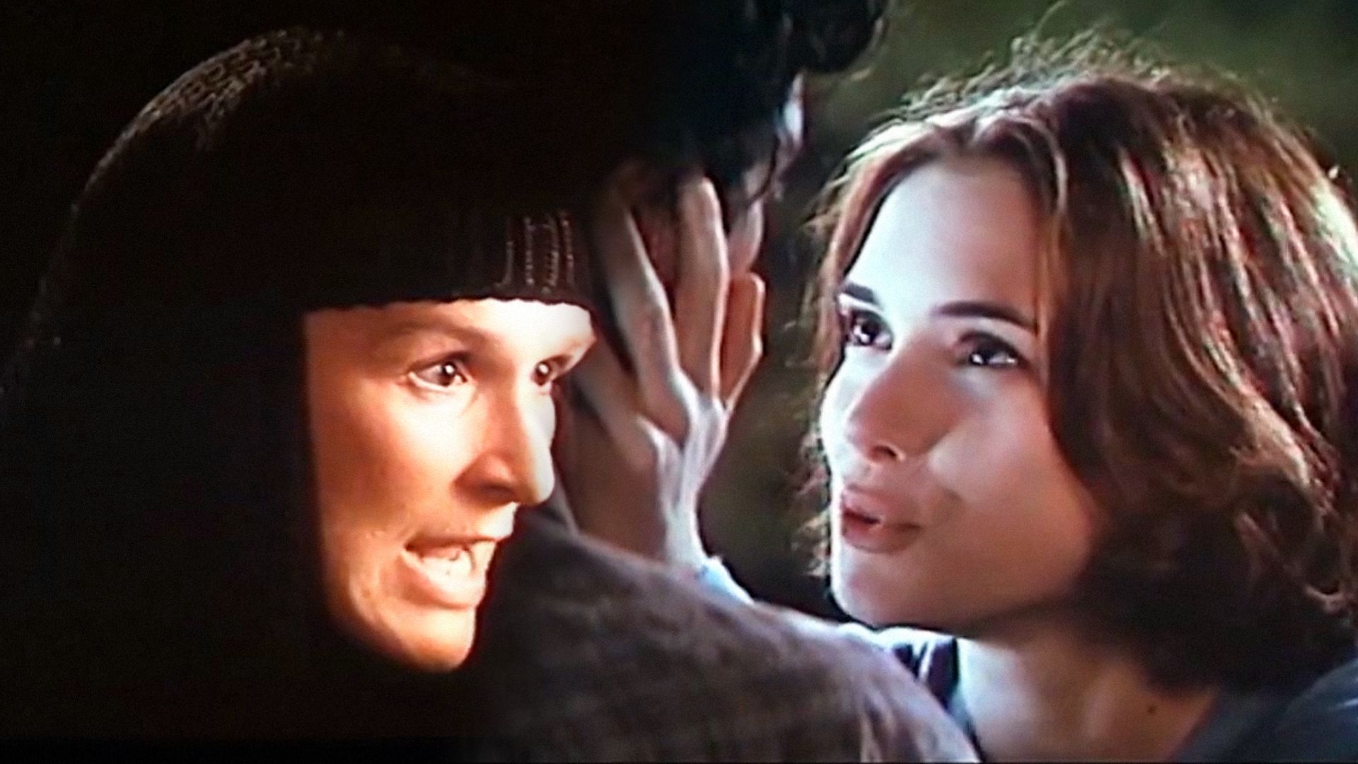 Mulher com roupa preta e boca aberta, à direita a atriz Winona Ryder segura o rosto de um homem com as palmas das mãos