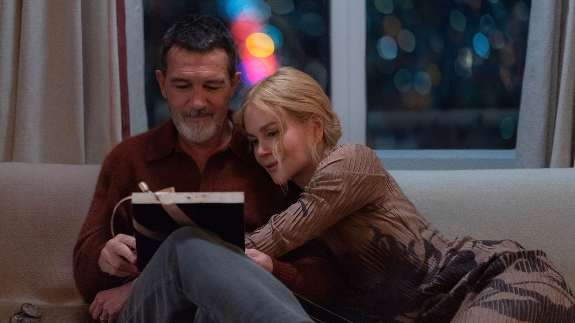 Antonio Banderas e Nicole Kidman sentados num sofá abraçados, cena do filme