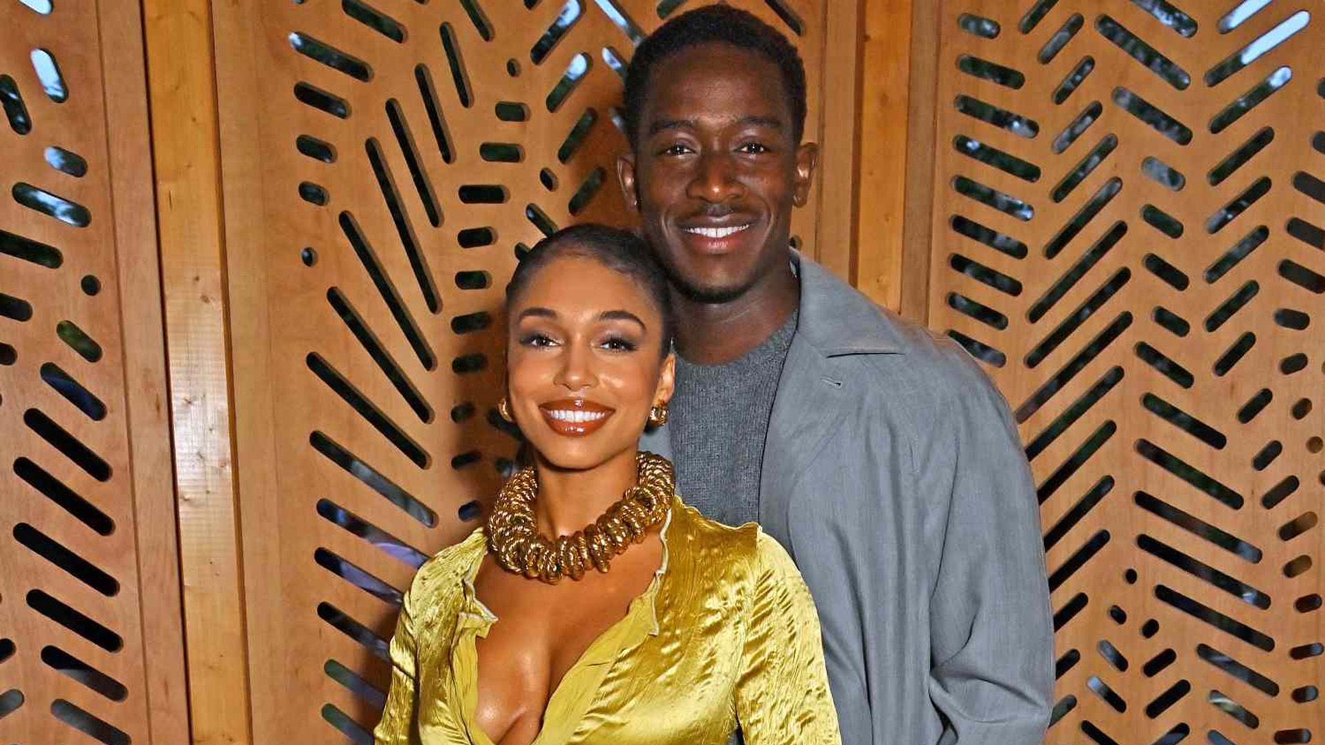 Damson Idris com uma camisa cinzenta e Lori Harvey com uma blusa amarela