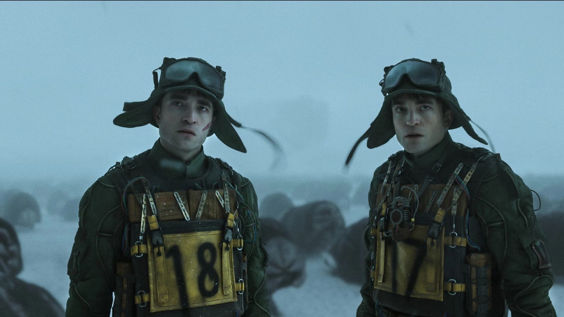 Dois Robert Pattinsons em roupas iguais com os números 17 e 18, still do filme