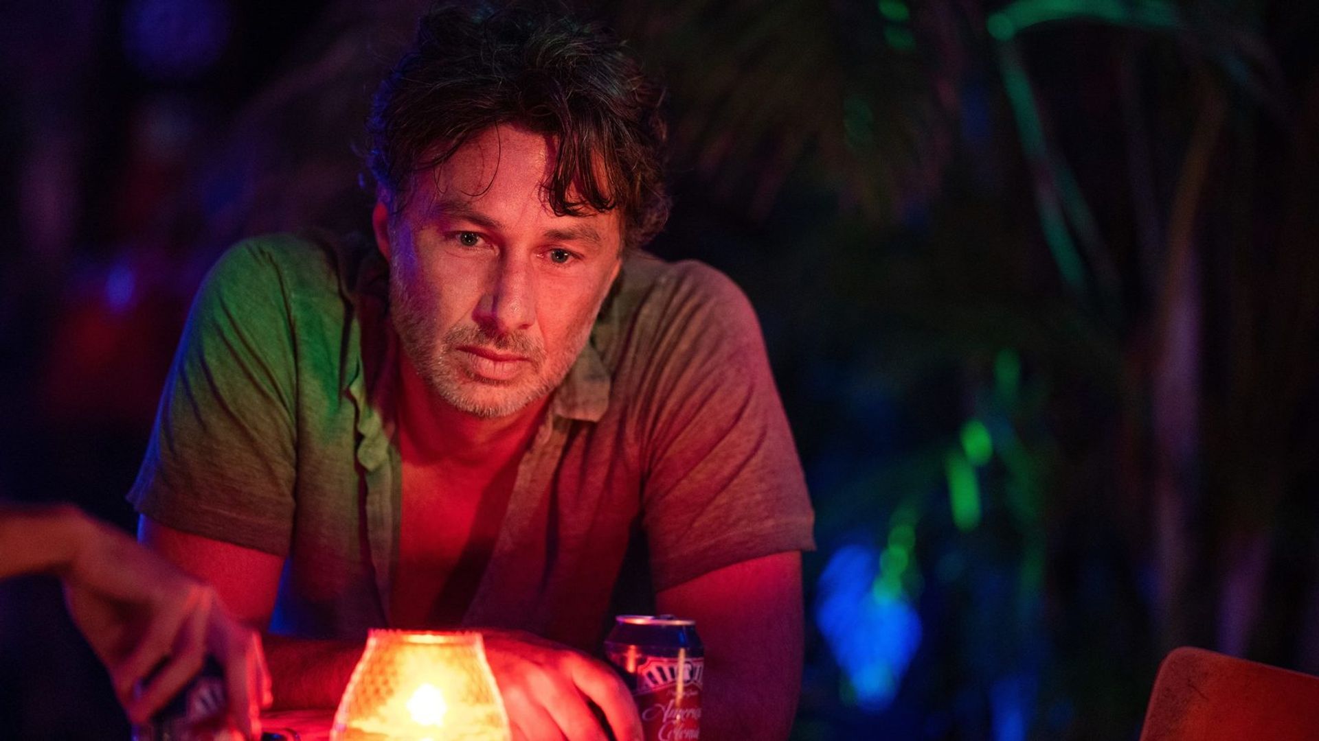 Zach Braff bebe uma bebida sob luz néon