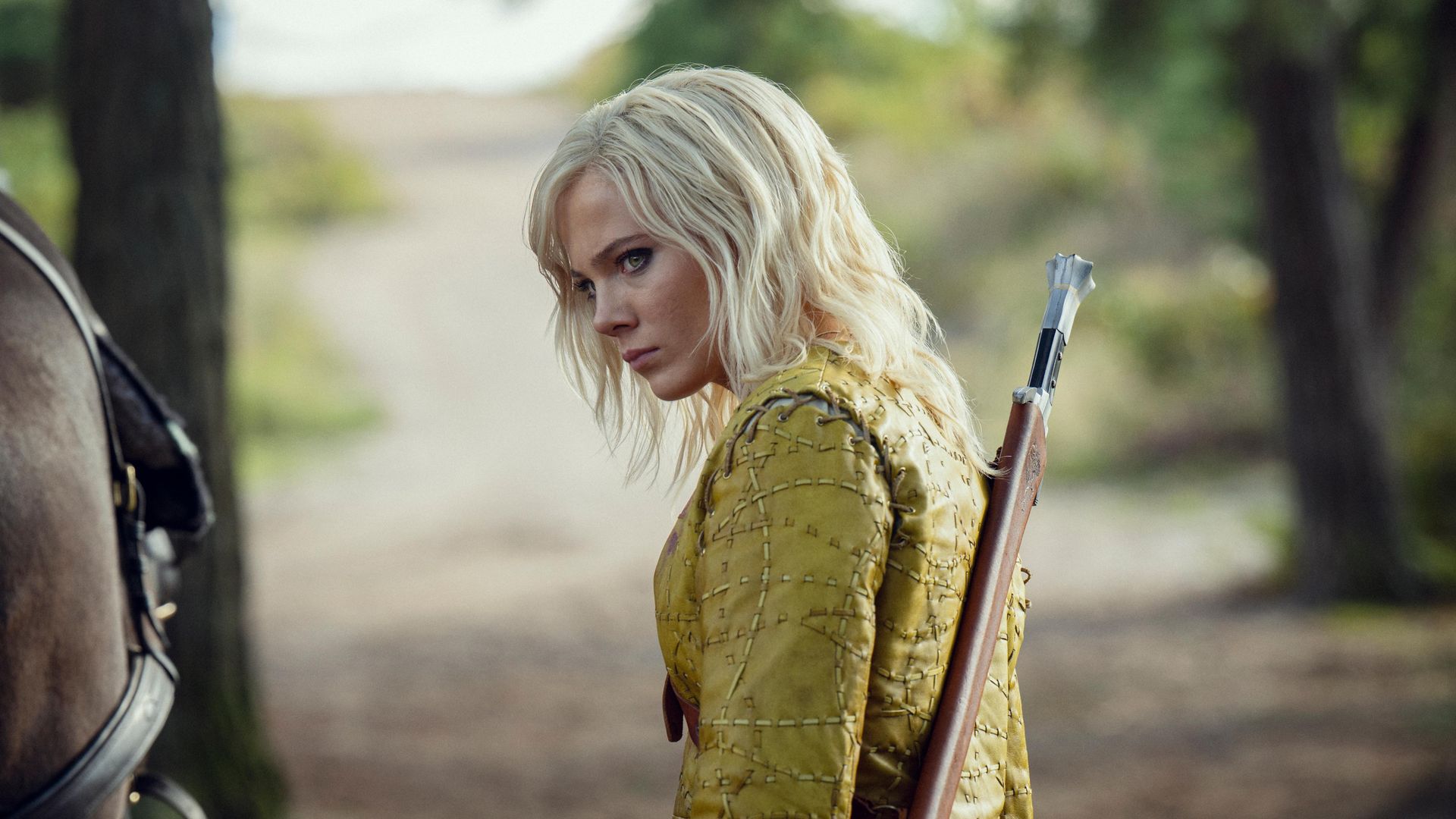 Freya Allan com roupa medieval amarela a olhar para o lado
