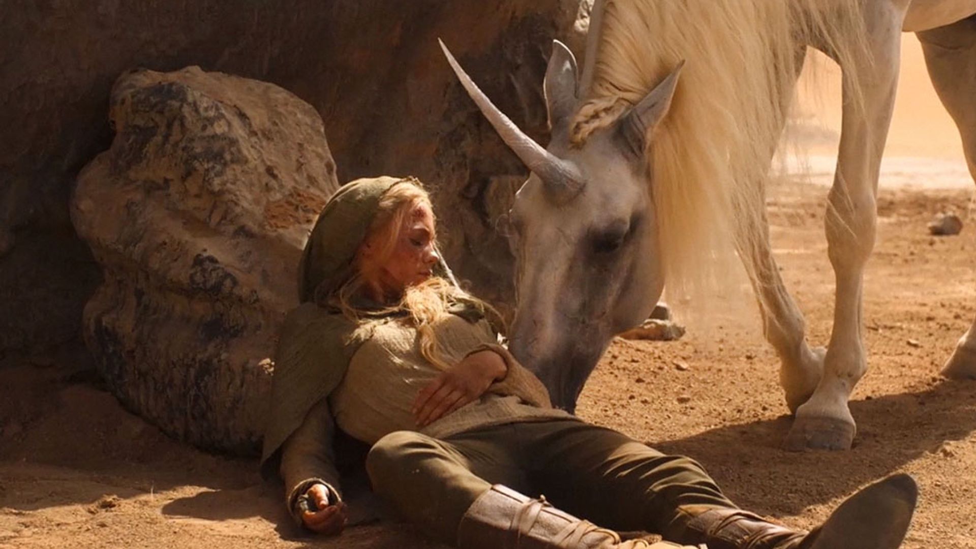Freya Allan a acariciar um cavalo com um chifre, cena da série The Witcher