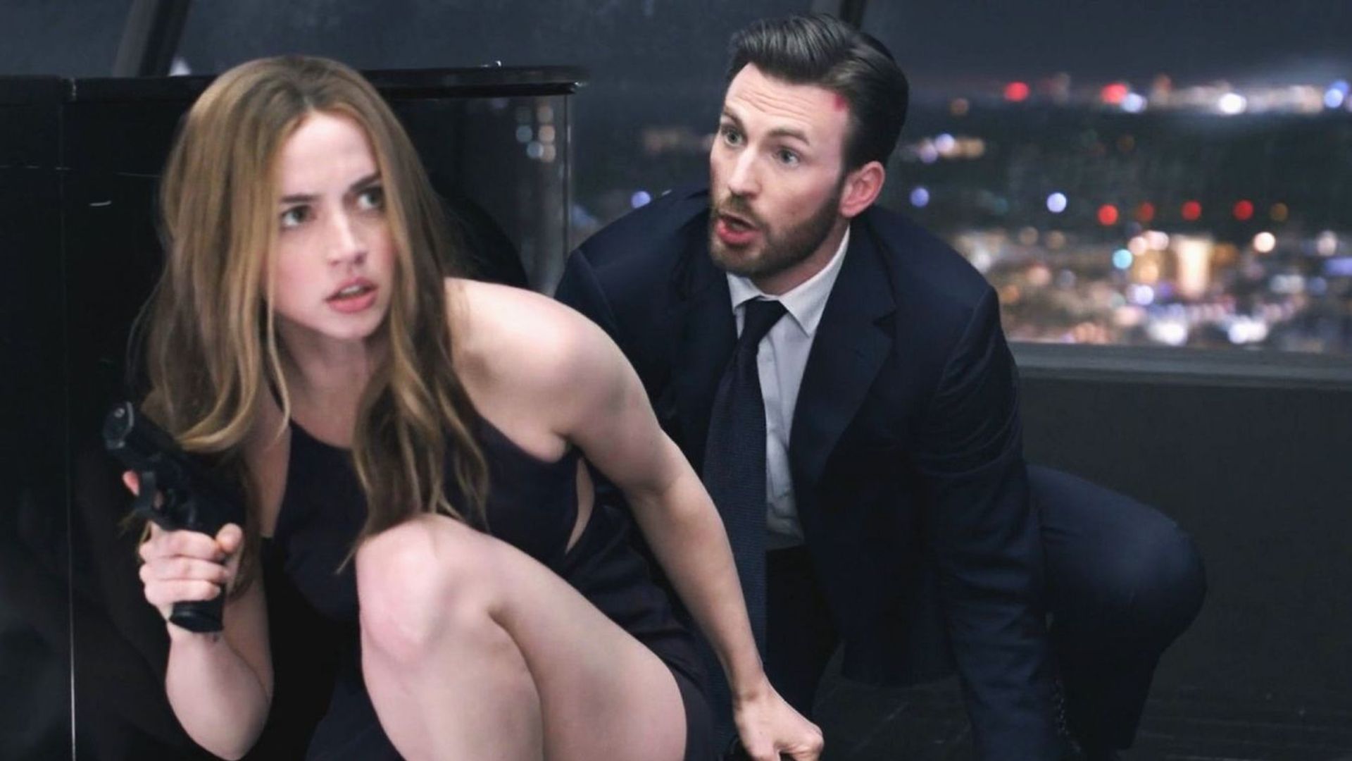 Ana de Armas e Chris Evans parecem tensos e concentrados como se estivessem se preparando para a ação