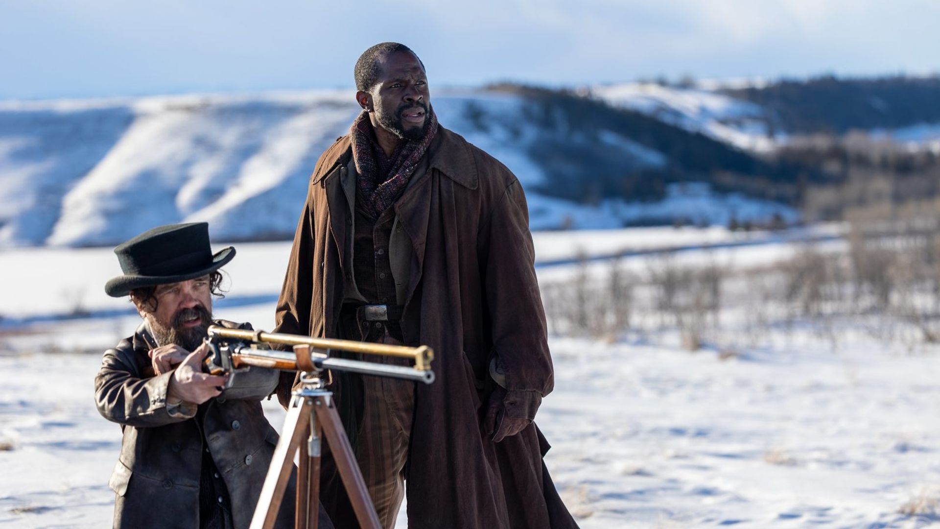 Peter Dinklage e Gbenga Akinnagbe na neve, um apontando uma espingarda montada num tripé, o outro olhando para a distância