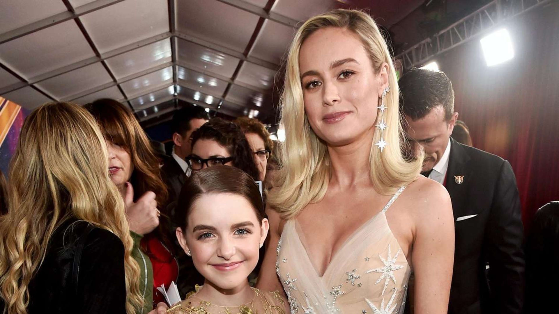 Mckenna Grace e Brie Larson posam juntas com Brie abraçando a garota