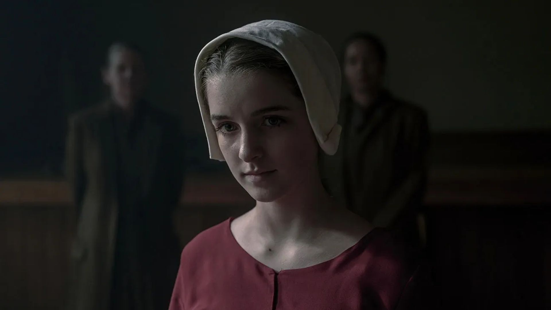 Mckenna Grace com uma touca e roupas de época, cena de The Handmaid's Tale