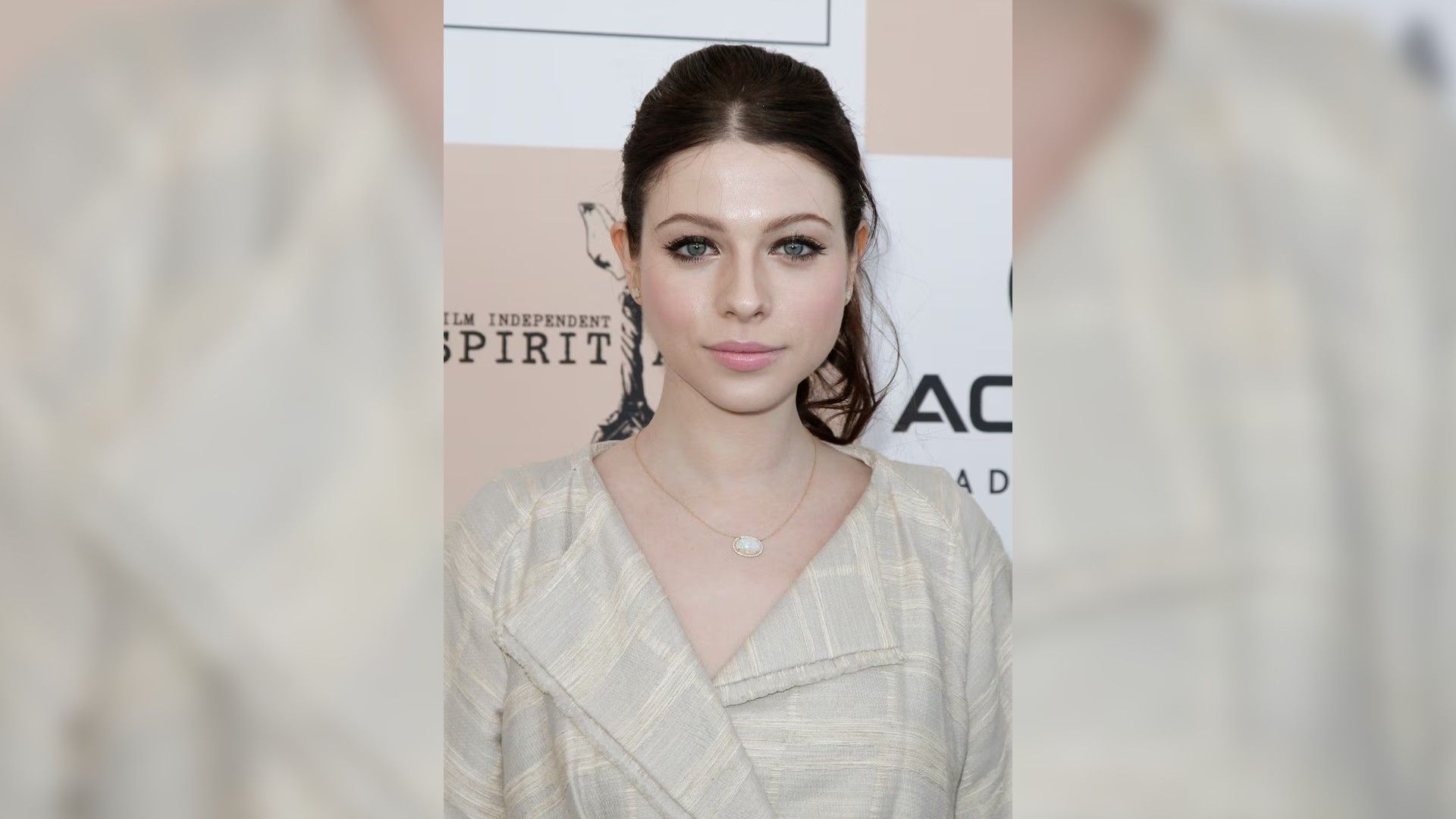 Michelle Trachtenberg com uma camisa branca, cabelo preso para trás