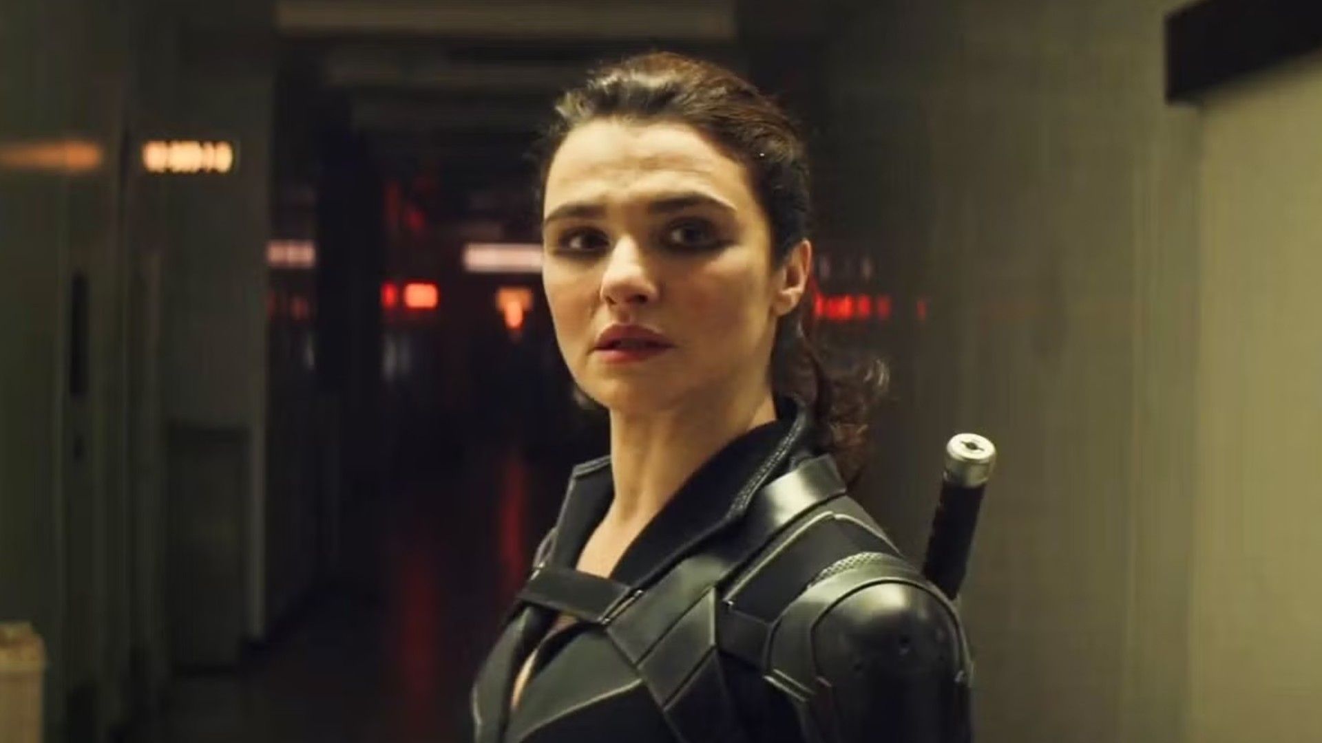 A atriz Rachel Weisz com o cabelo apanhado num rabo de cavalo, vestindo um fato de super-herói preto