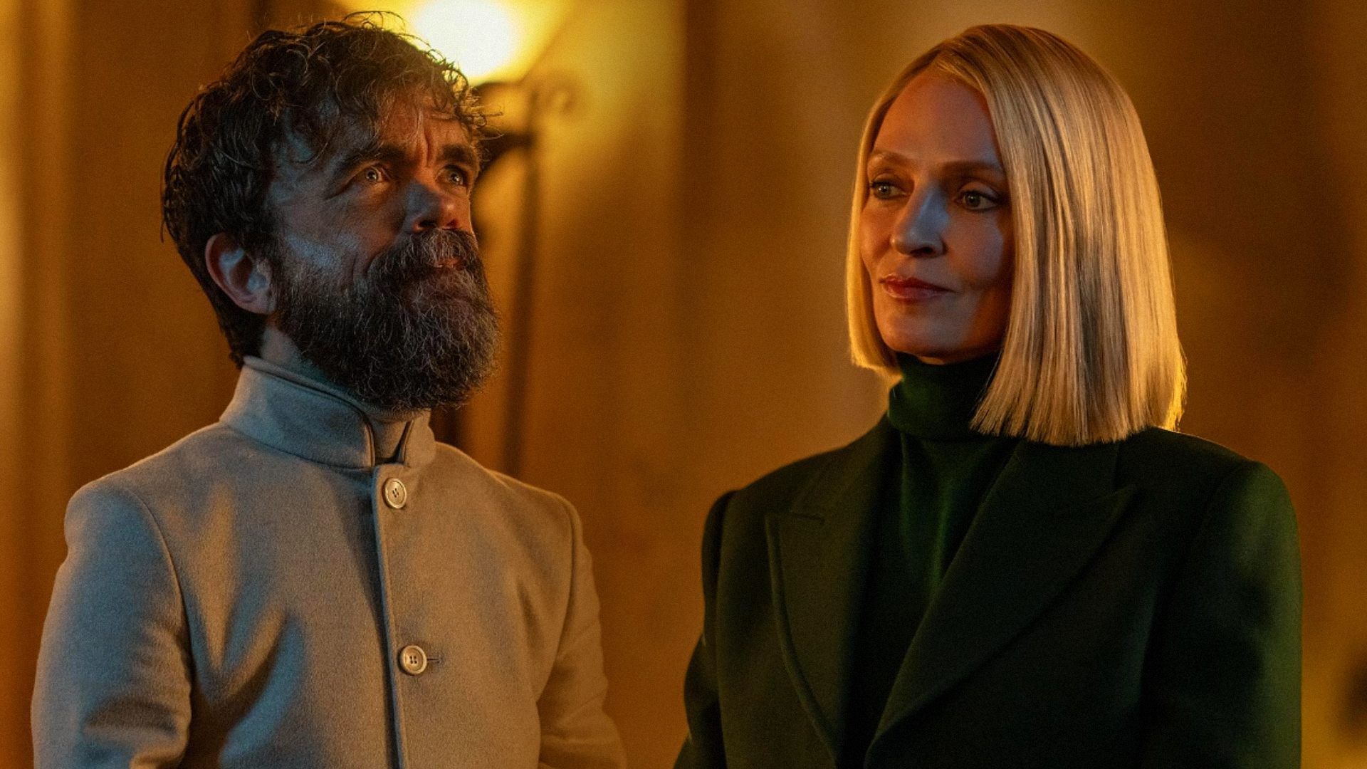 O ator Peter Dinklage com cabelo curto e vestindo roupa branca, a atriz Uma Thurman com um blazer verde