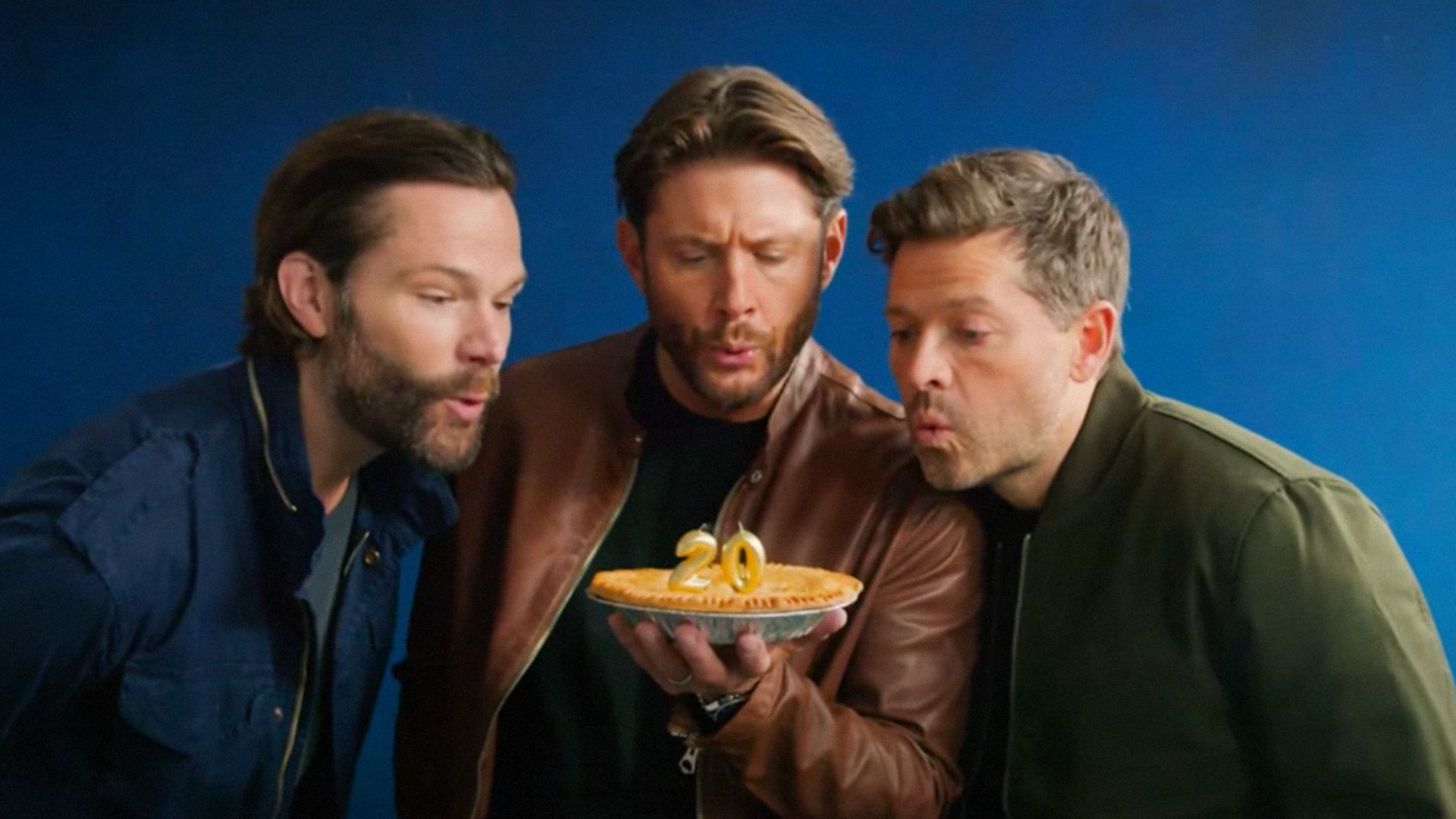 Os atores Jared Padalecki, Jensen Ackles e Misha Collins sopram as velas de um bolo
