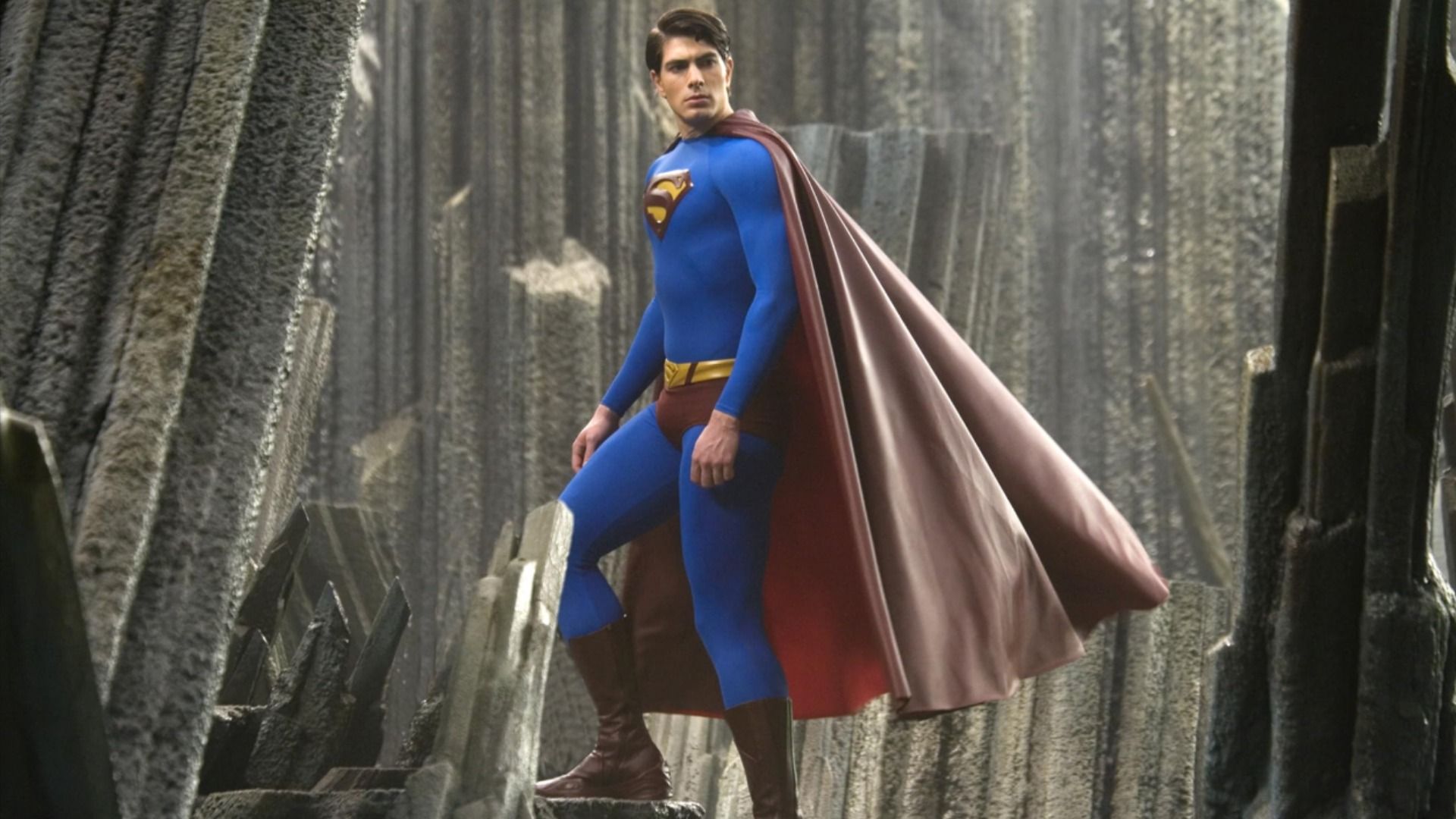 O ator Brandon Routh num fato de super-herói azul e vermelho com a letra S no peito sobe as escadas
