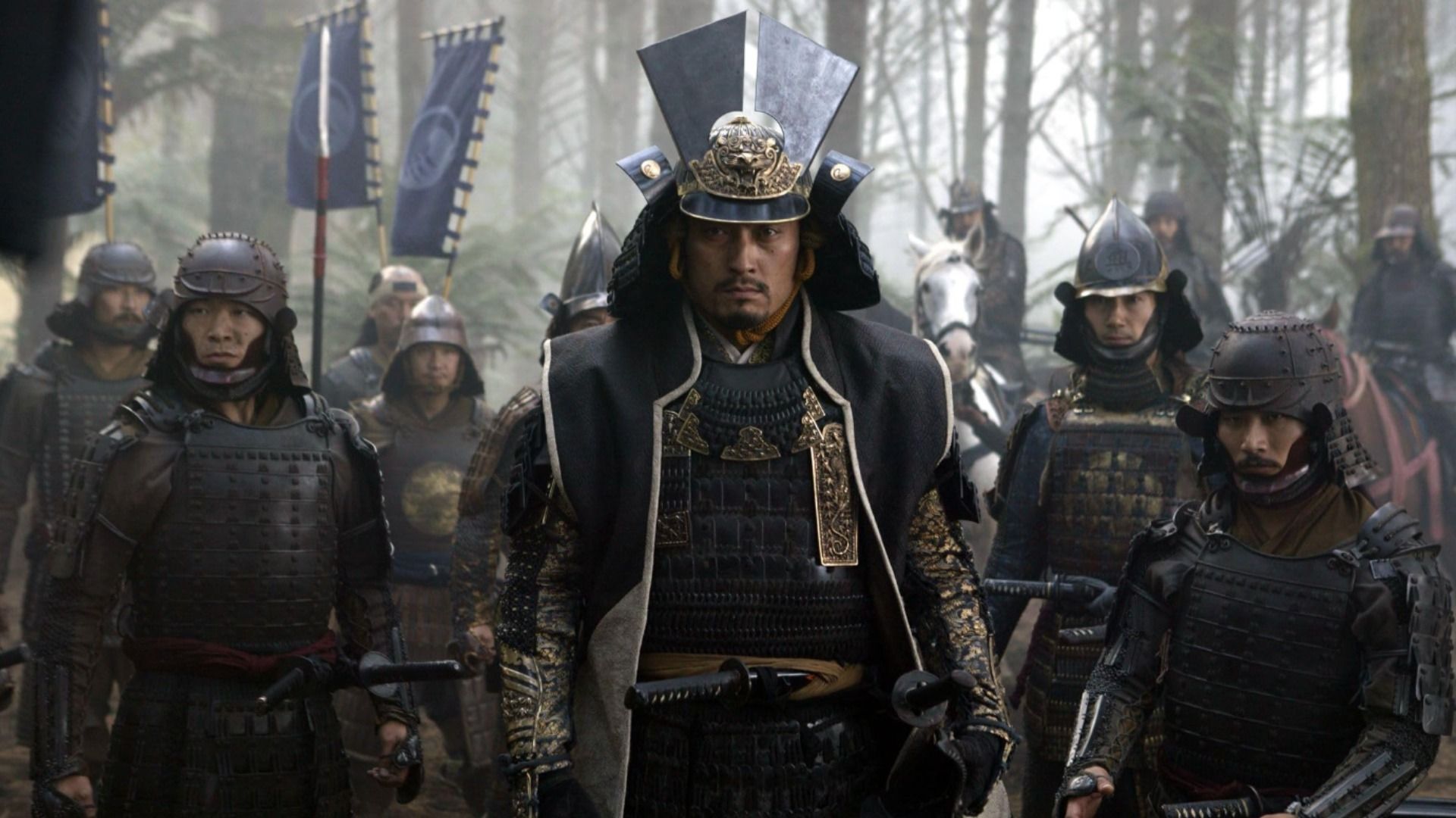 O ator Ken Watanabe em armadura samurai escura rodeado por outros samurais
