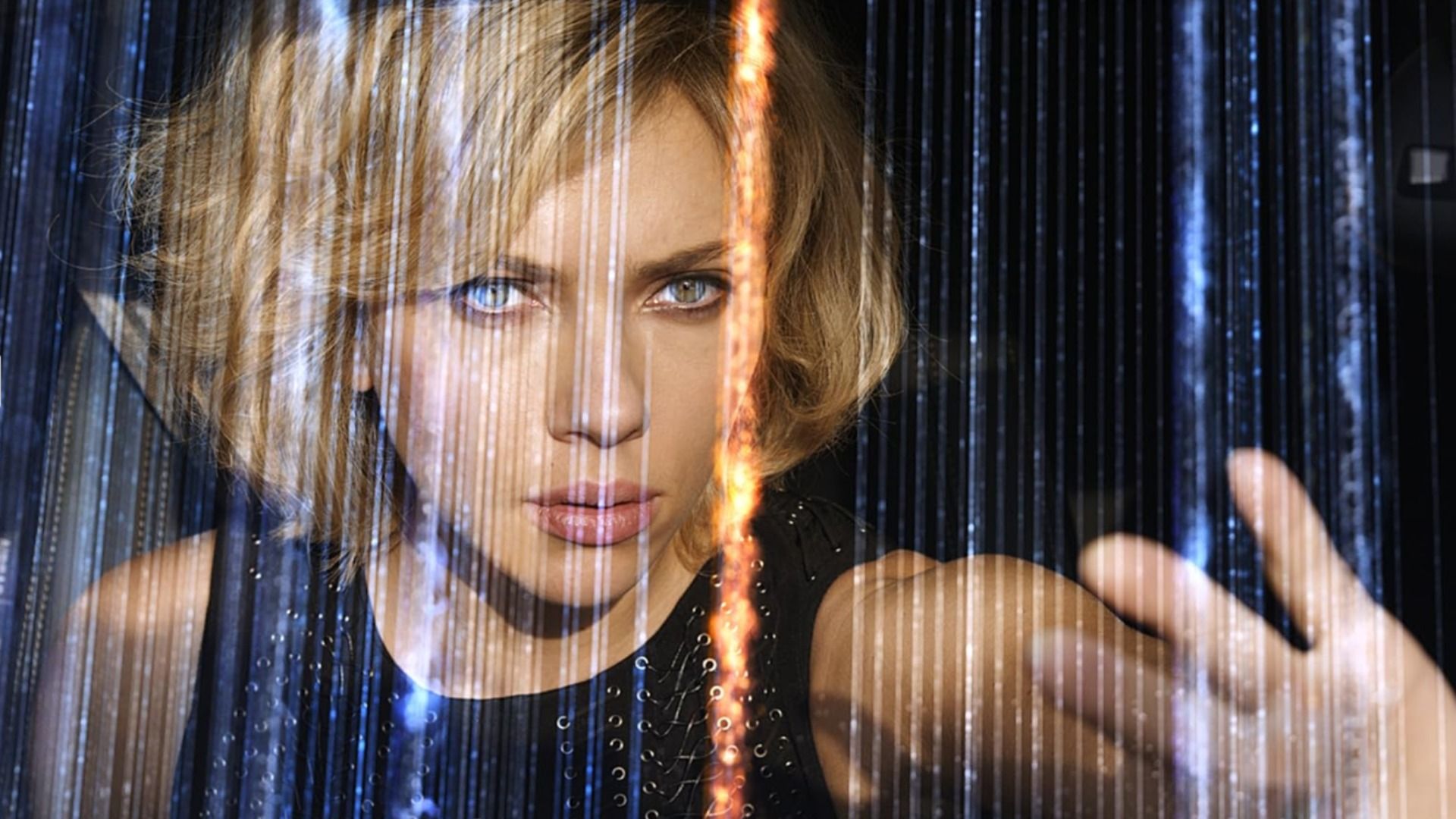 A atriz Scarlett Johansson num vestido preto com a mão levantada entre linhas cintilantes