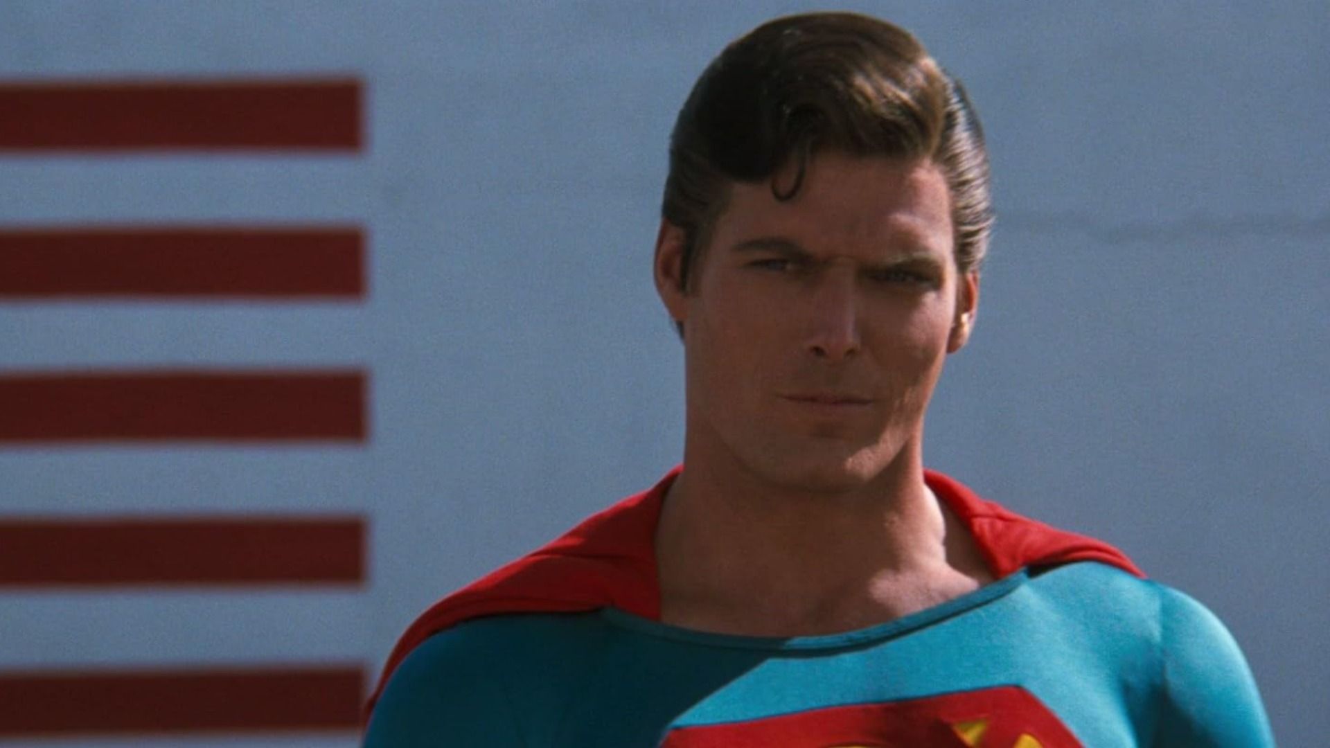 O ator Christopher Reeve com o fato azul e vermelho do Superman a olhar ameaçadoramente para o lado