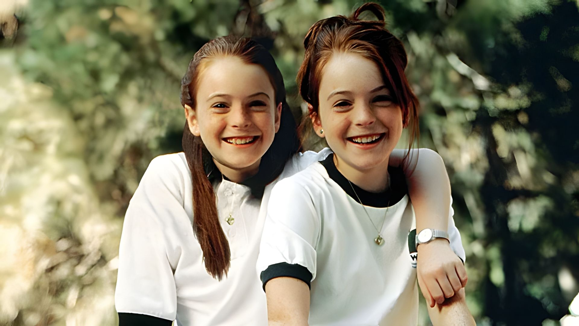 Lindsay Lohan como gémeas, ambas vestindo t-shirts brancas contra um fundo verde