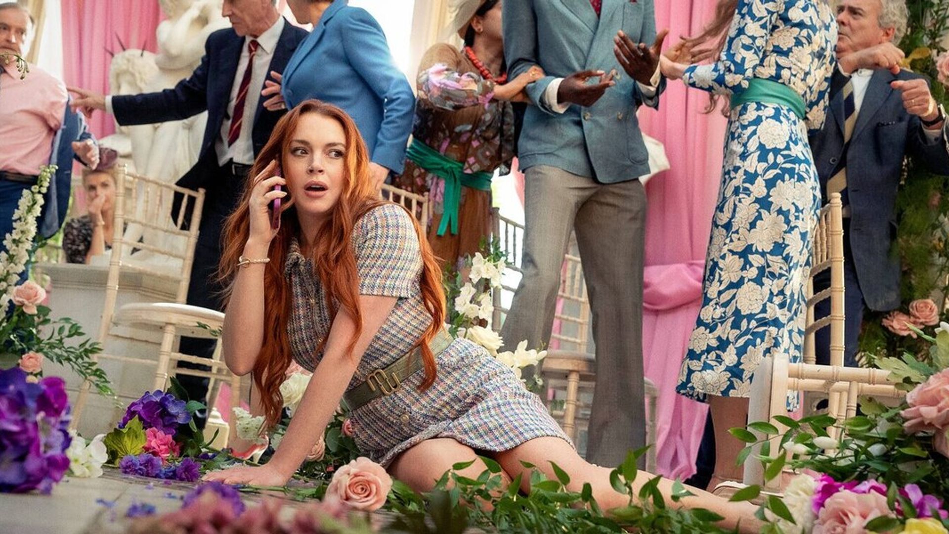 Lindsay Lohan caiu no chão entre flores enquanto fala ao telefone com o caos da cerimónia de casamento ao fundo