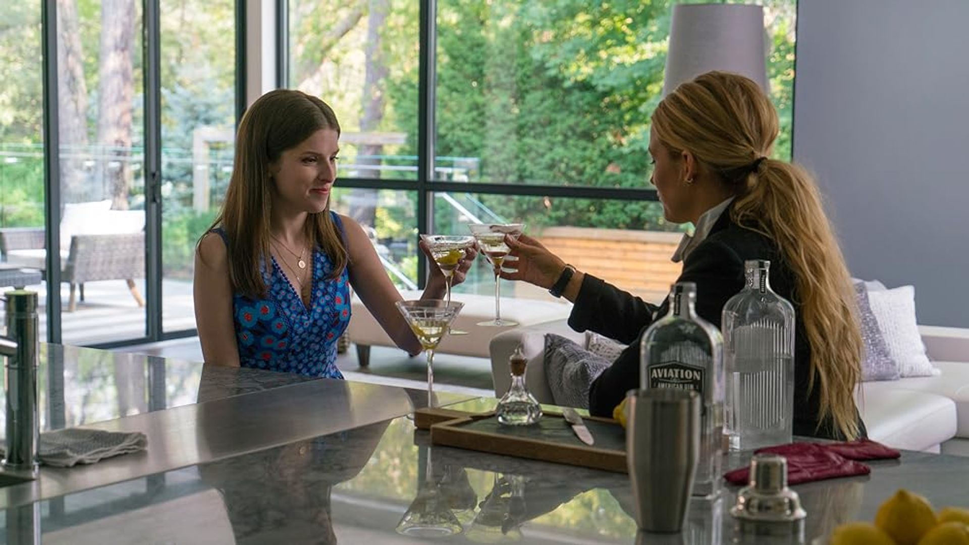 Anna Kendrick e Blake Lively a brindar com copos de vinho na cozinha