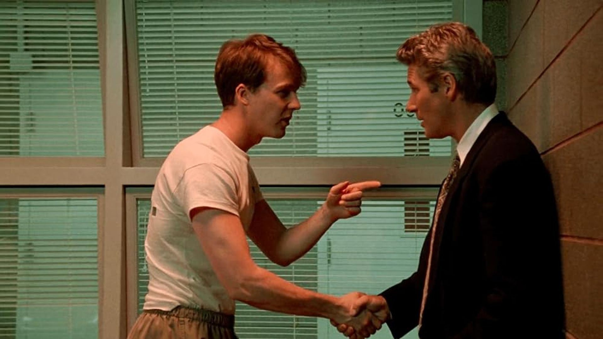Edward Norton numa t-shirt a apertar a mão de Richard Gere de fato, apontando-lhe o dedo