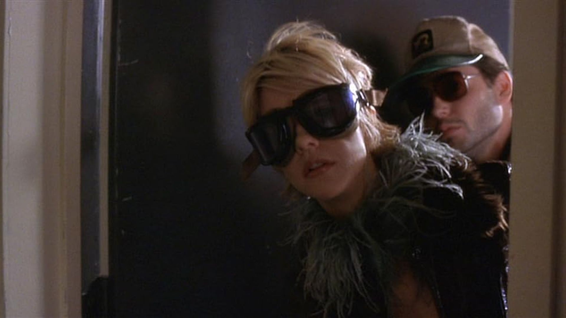Meg Ryan e Matthew Broderick com óculos escuros a espreitar por trás de uma porta