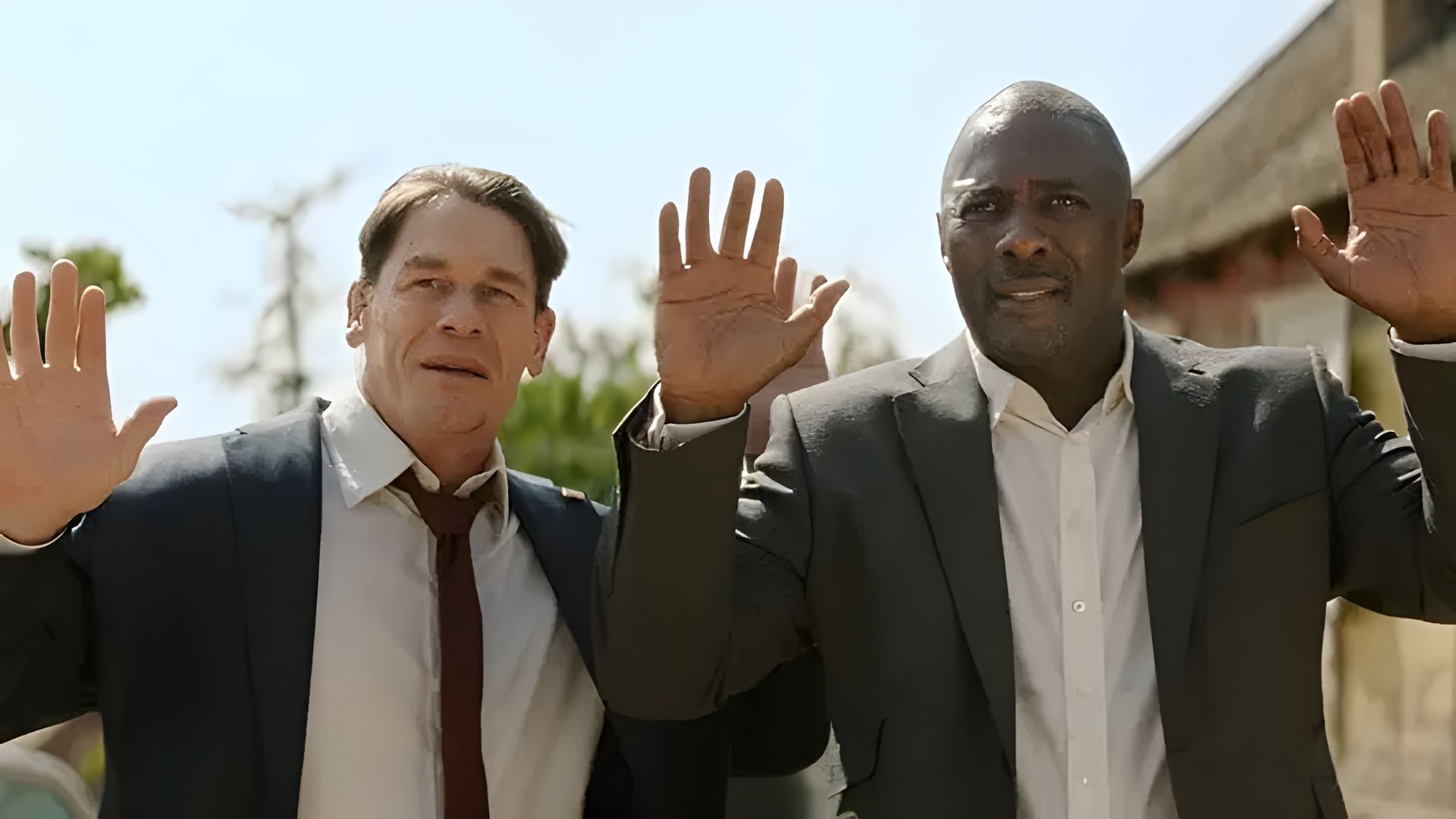 John Cena e Idris Elba de fato levantando as mãos, cena de um filme de ação