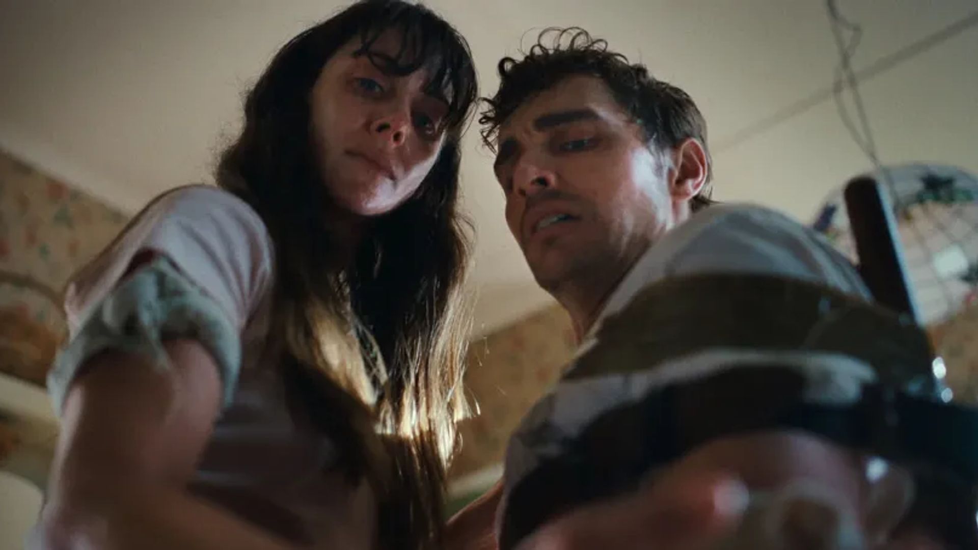 Alison Brie e Dave Franco olham para a câmara com expressões preocupadas, filmados de um ângulo baixo