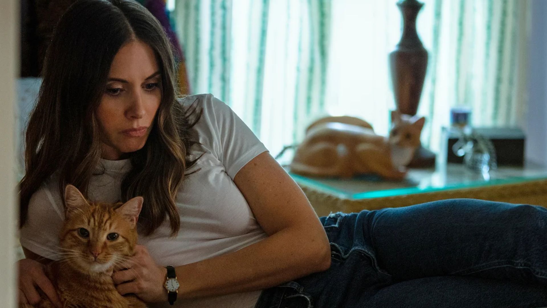 Alison Brie deitada numa cama com um gato nos braços