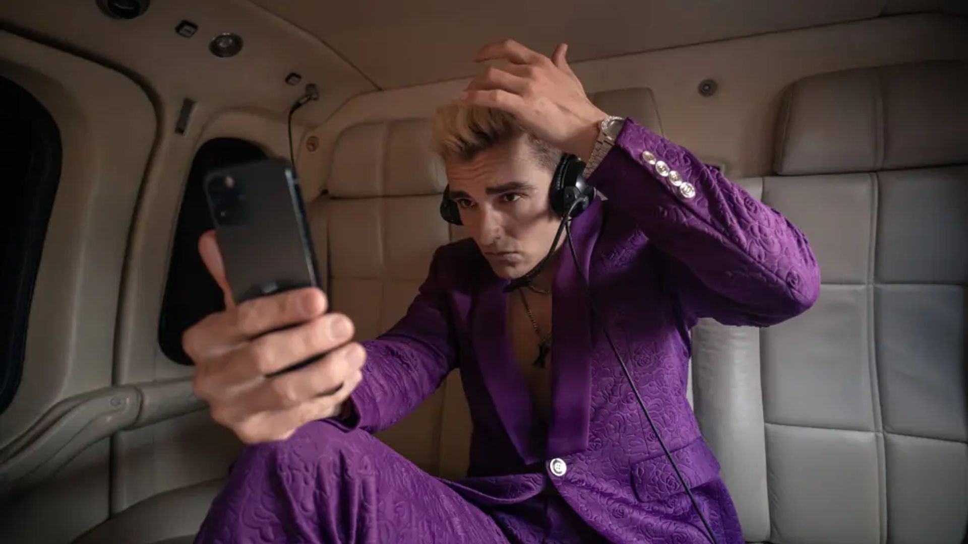 Dave Franco num fato roxo olhando para o telemóvel, cena da série The Afterparty