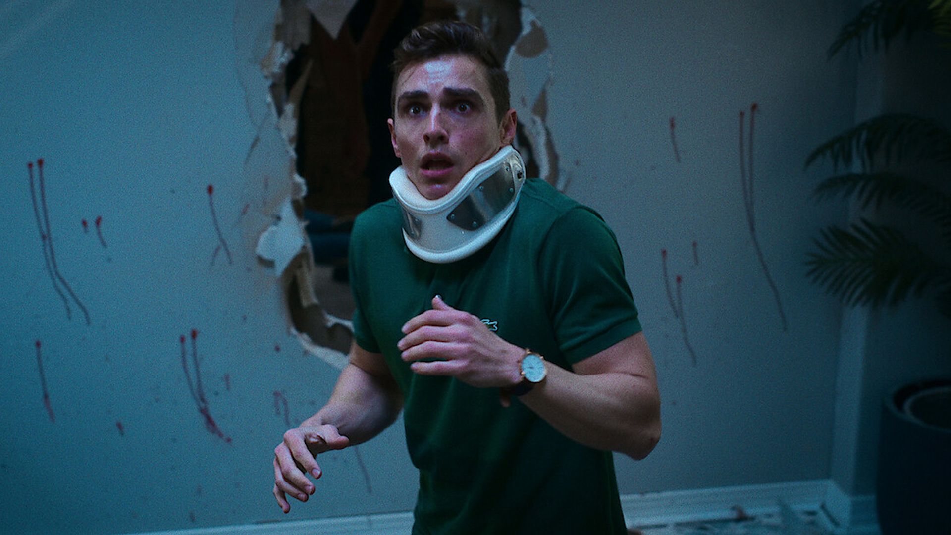 Dave Franco com uma cinta ortopédica no pescoço e uma expressão assustada no rosto
