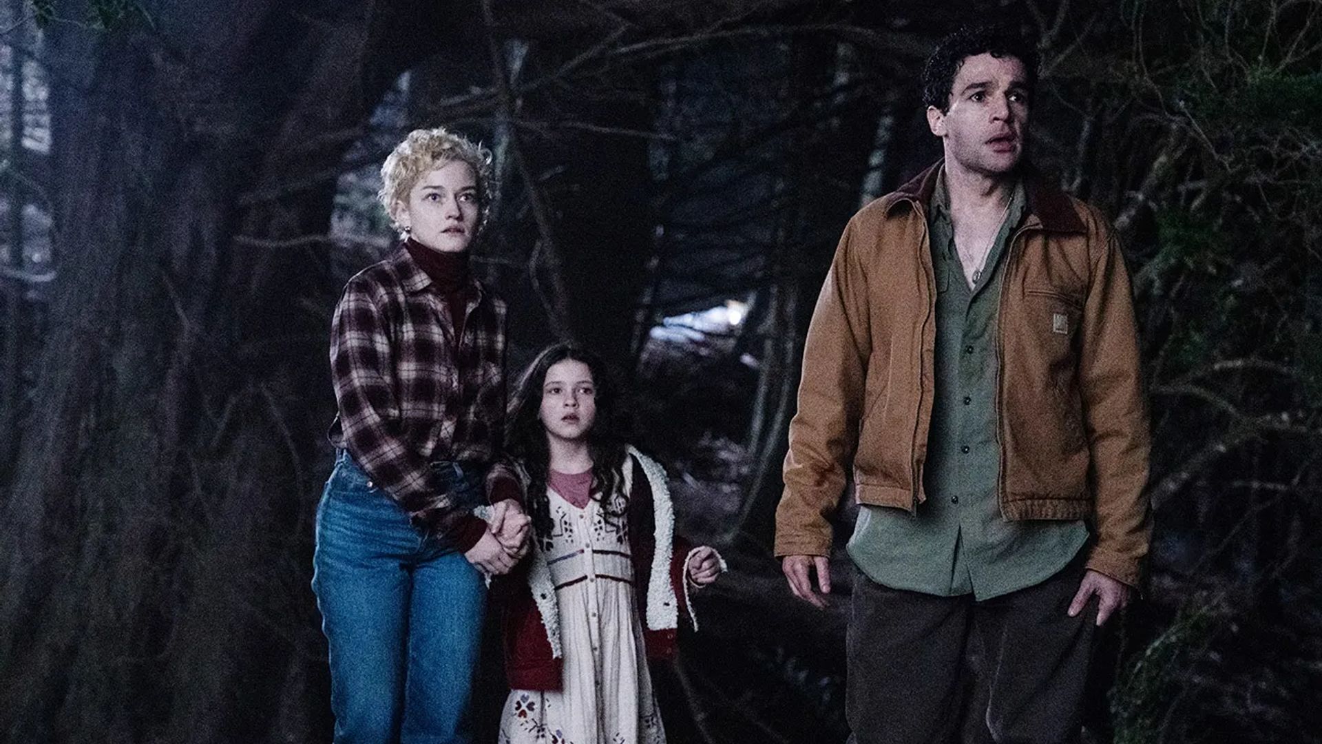 Julia Garner, Christopher Abbott e Matilda Firth numa floresta noturna, still do filme "Wolf Man"