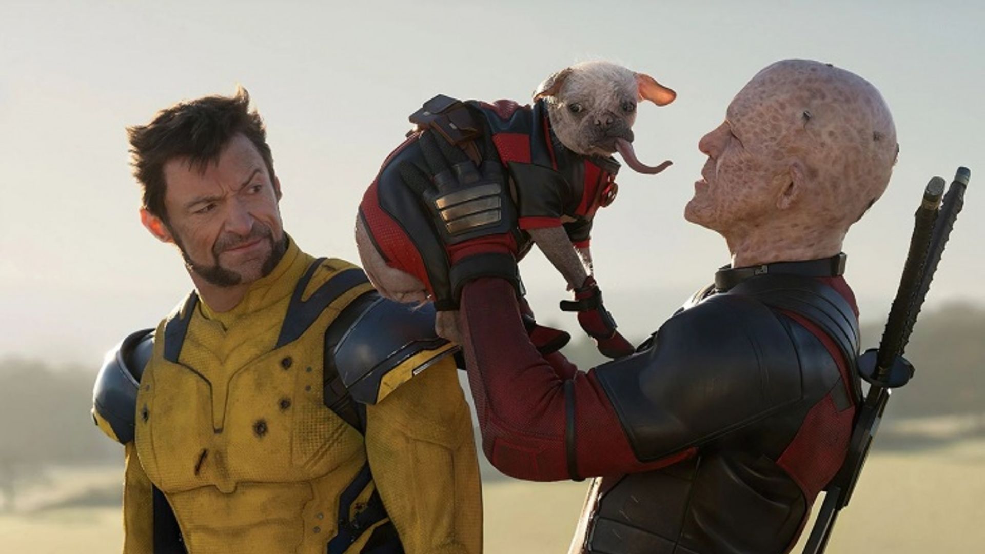 Deadpool segurando um cão fantasiado enquanto Wolverine no seu fato amarelo os observa com surpresa