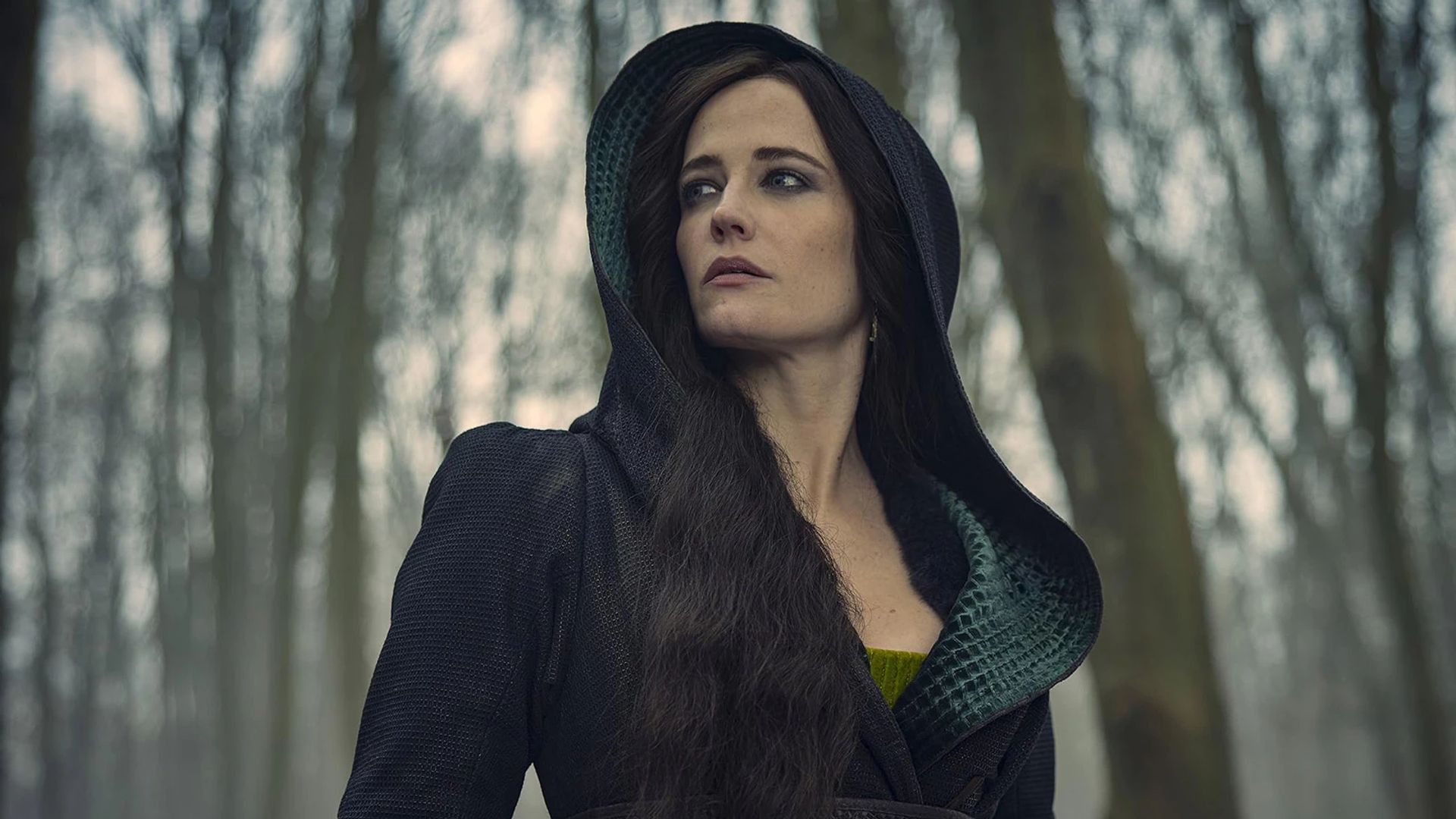 Eva Green num vestido preto com capuz contra um cenário de floresta invernal