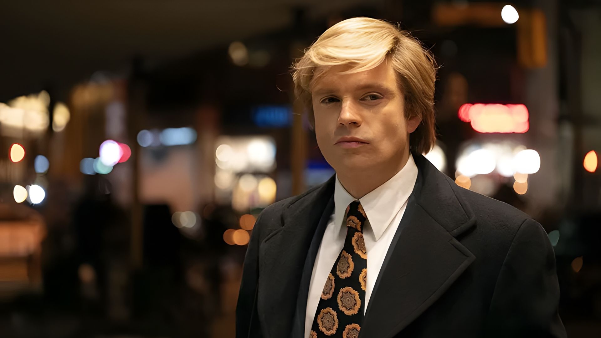 Sebastian Stan de fato e peruca branca olhando para a câmara