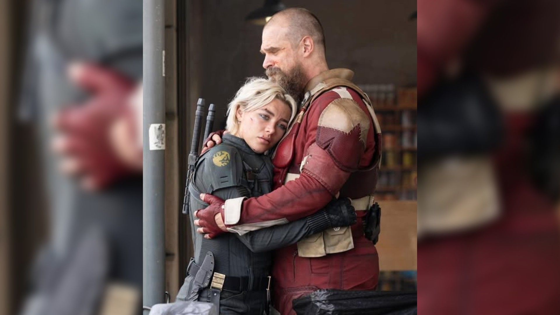 David Harbour e Florence Pugh em fatos de super-herói abraçados, vista de perfil
