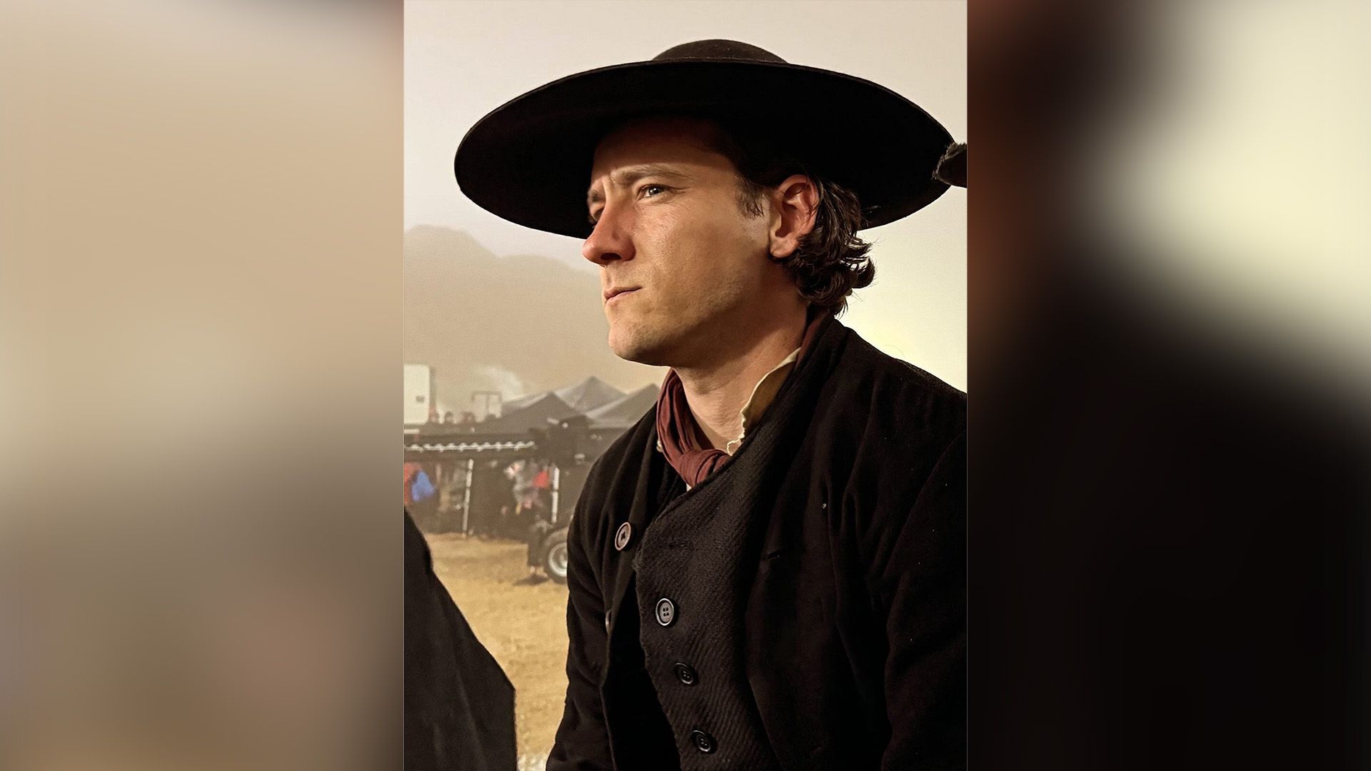 Lewis Pullman com casaco de lã preto e chapéu preto de abas largas