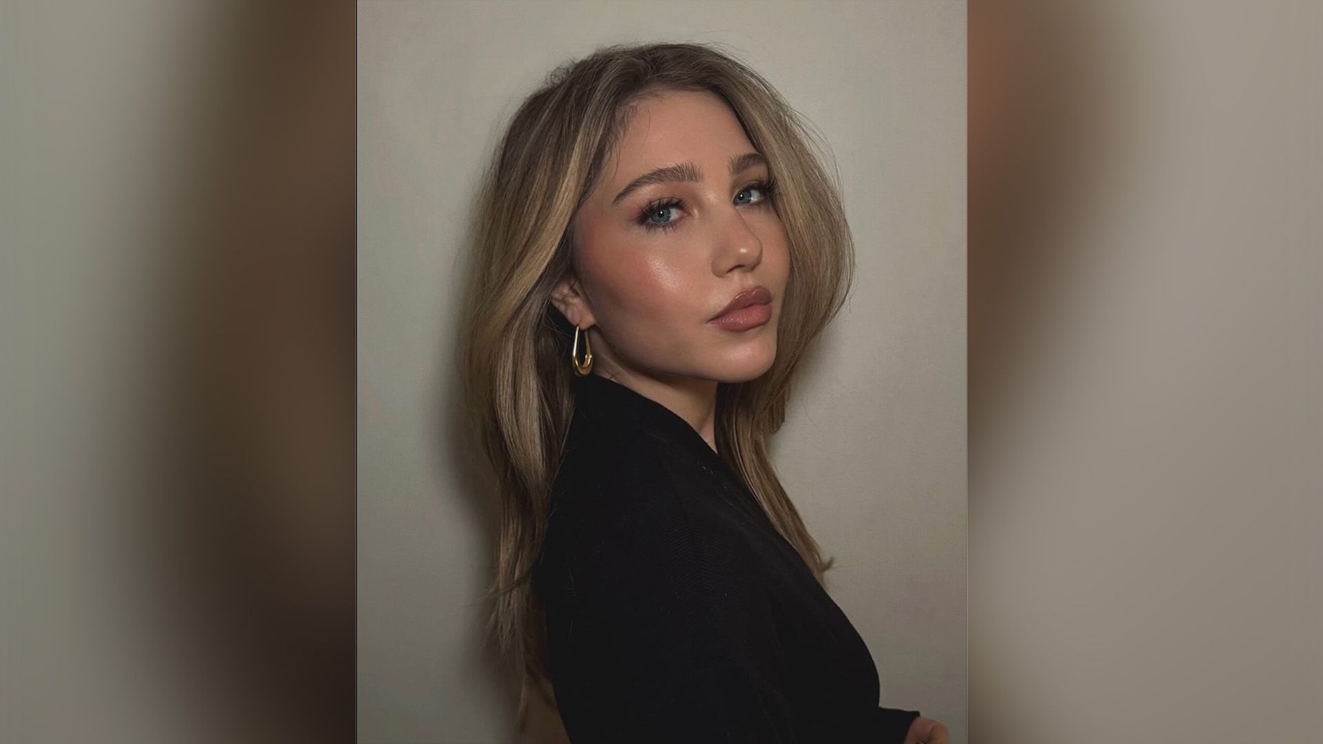 Ella Anderson com um blazer preto numa pose de três quartos com um brinco dourado