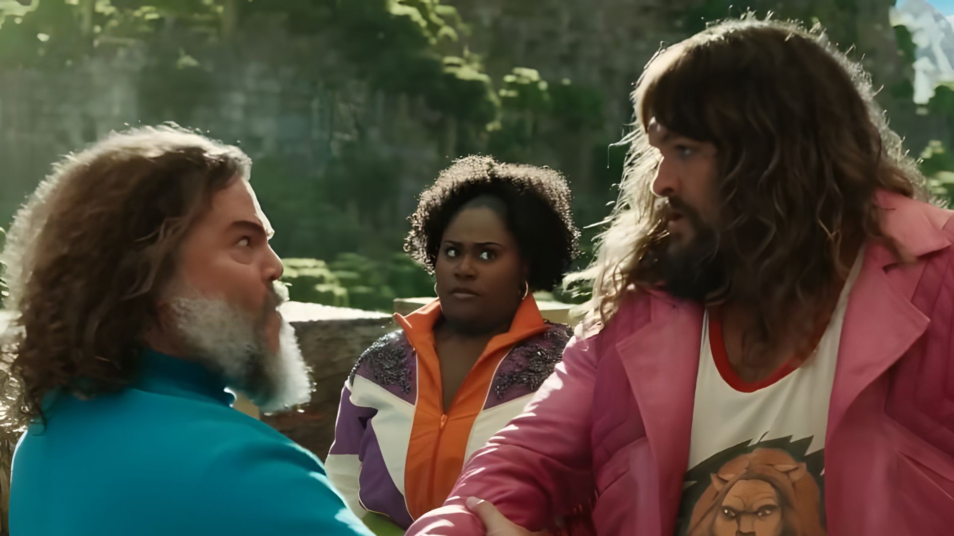 Jack Black numa t-shirt azul e Jason Momoa num casaco cor-de-rosa apertando vigorosamente as mãos